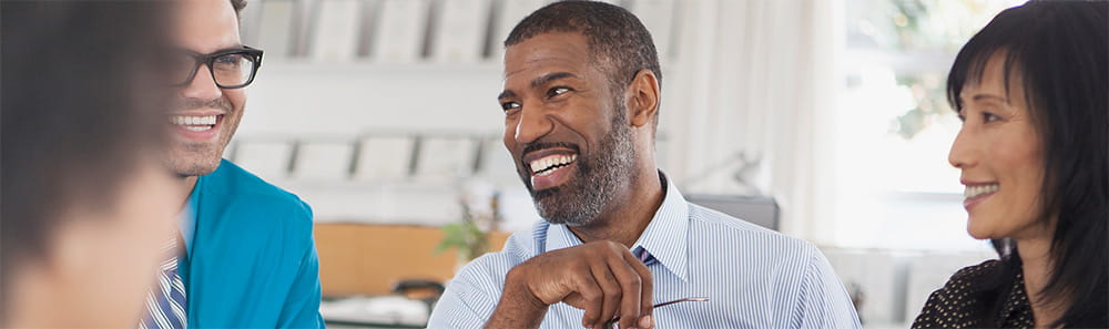 Three people laughing in a business meeting room